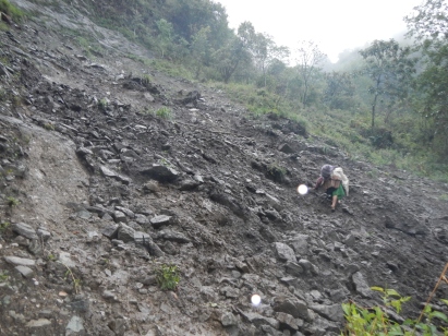 An old woman negotiating a track that had recently been hit by a localised landslide.